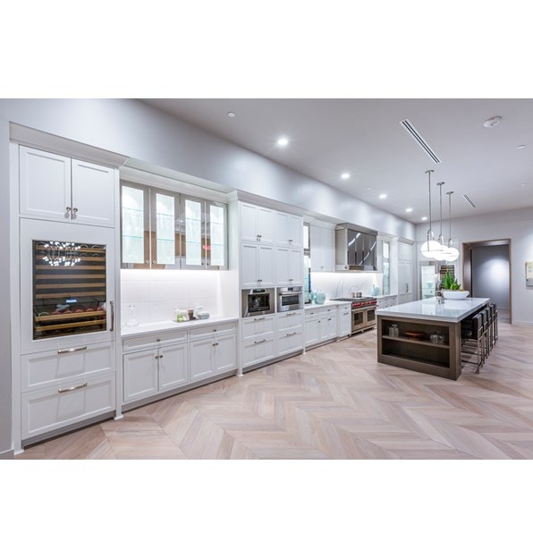 A white kitchen with many different installations and styles of Sub-Zero, Wolf, and Cove appliances. 