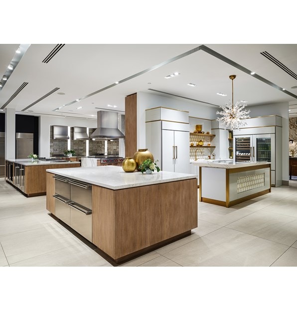 A white professional kitchen with white-marbled countertops and built-in Sub-Zero, Wolf, and Cove appliances
