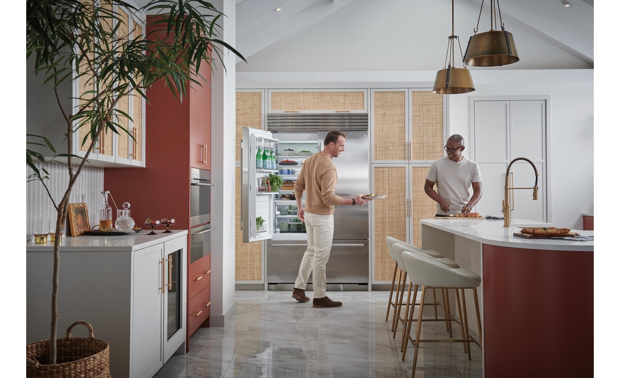 Two men smiling as they grab fresh food from their Sub-Zero 48 inch french door Classic Series stainless steel Refrigerator