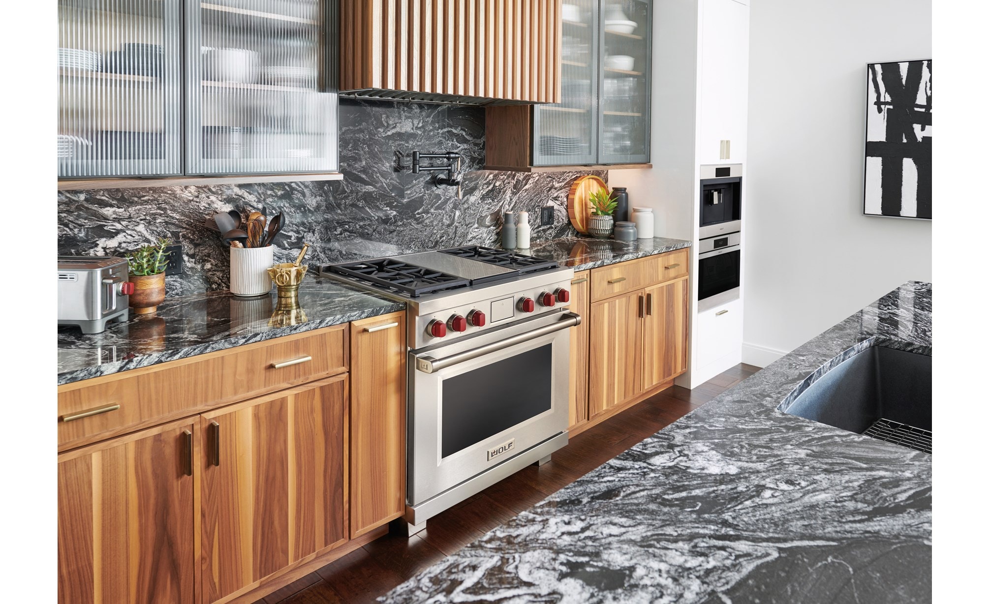 Wolf 36" Dual Fuel Range displayed in a modern kitchen condo design featuring custom cabinetry and rich marble countertops.