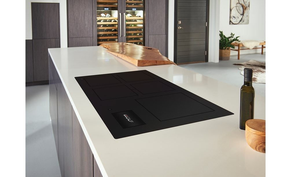 Wolf 36 Contemporary Induction Cooktop (CI36560C/B) featured in a modern kitchen design, blending seamlessly into smooth white countertops with warm wood tone cabinets.