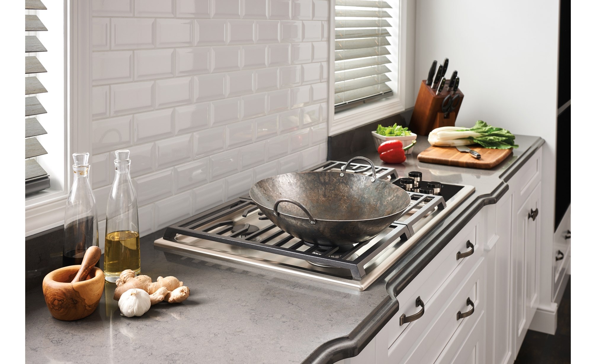 The Wolf 36" Transitional Gas Cooktop 5 Burners (CG365T/S) shown set in rich granite countertop against textured white brick backsplash