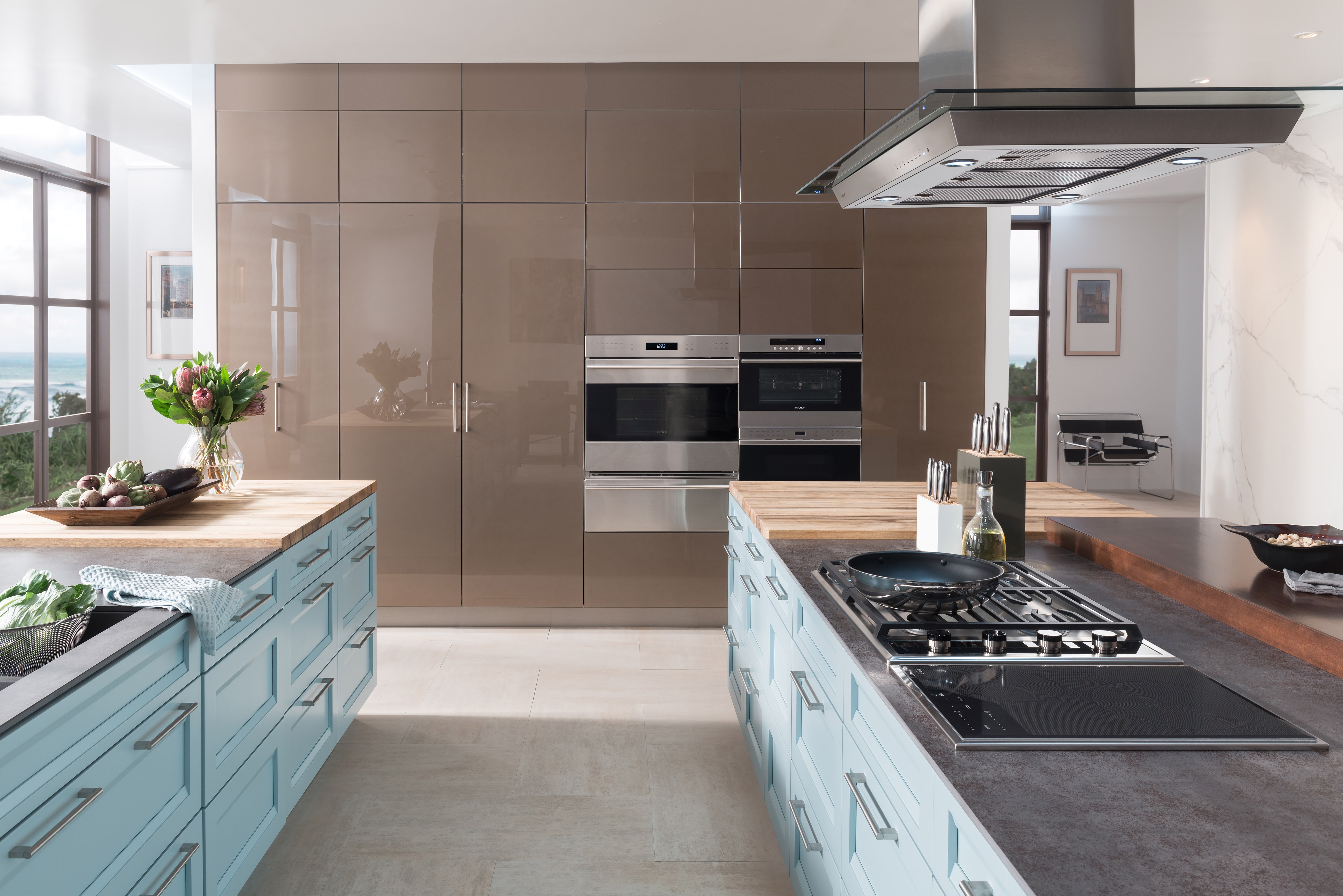 The Wolf 15" Transitional Induction Cooktop (CI152TF/S) shown with Wolf 45" Cooktop Island Hood - Glass (VI45G) in large open kitchen