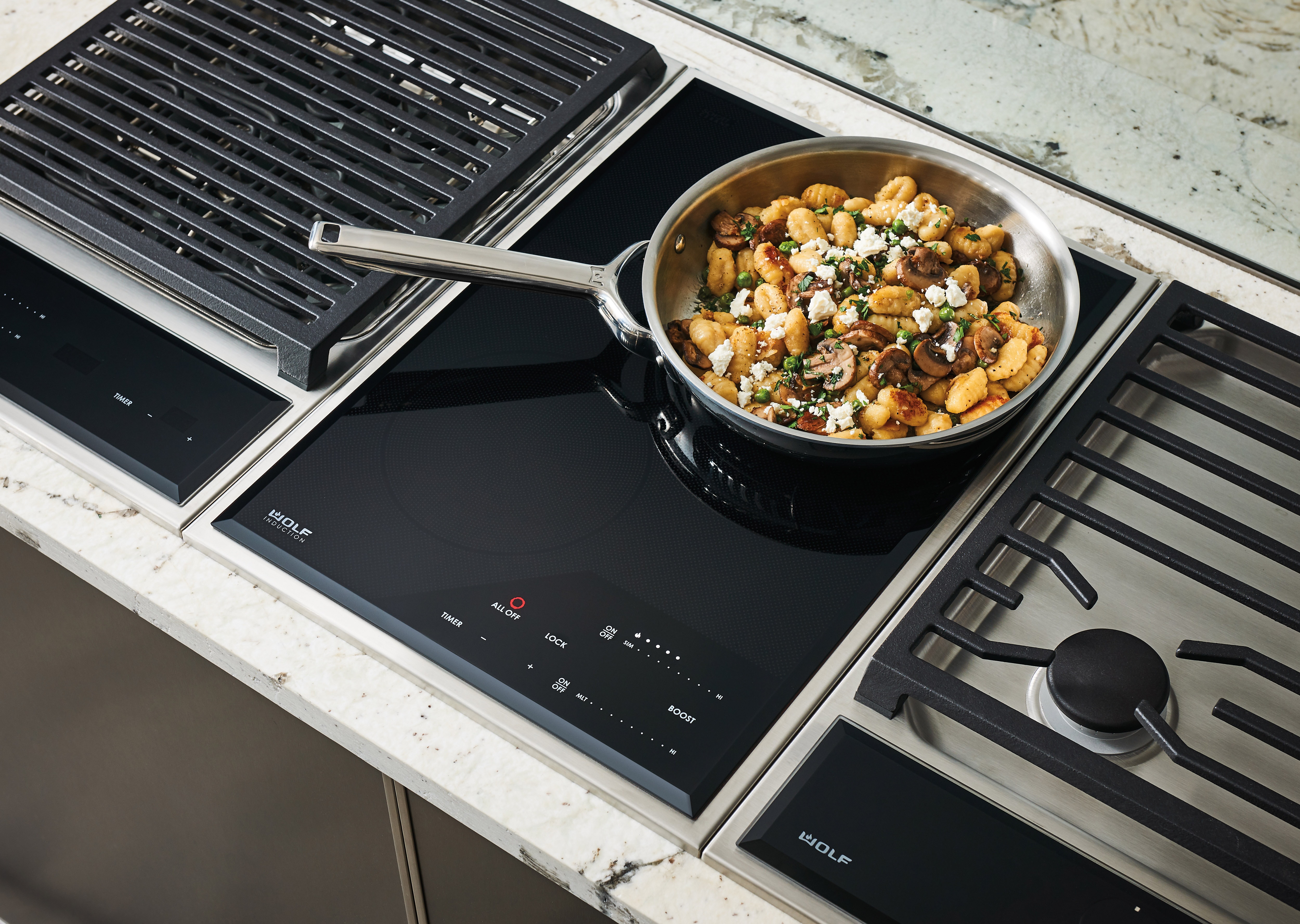 Wolf 15" transitional induction cooktop module (CI152TFS) paired with a 15" transitional grill module (GM15TFS) and 15" transitional gas cooktop module (CE152TFS)