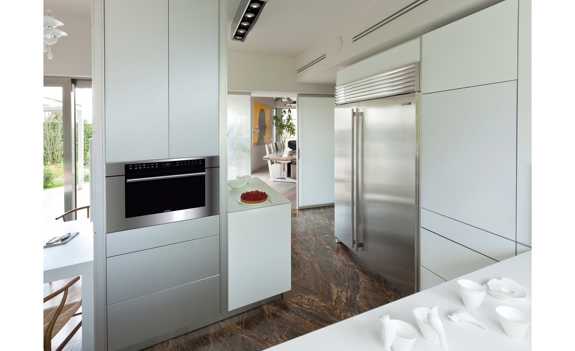 Wolf 30" M Series Transitional Drop-Down Door Microwave Oven (MDD30TM/S/TH) shown blending seamlessly between smooth panel cabinetry.