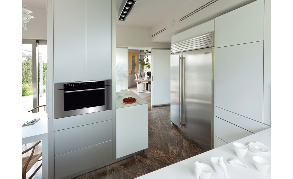 Wolf 30" M Series Transitional Drop-Down Door Microwave Oven (MDD30TM/S/TH) shown blending seamlessly between smooth panel cabinetry.