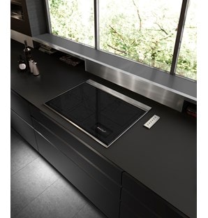 Wolf 30" Transitional Induction Cooktop (CI30460T/S) displayed in a sleek ultra modern kitchen design featuring smooth black countertops, stainless steel backsplash and handleless cabinets 