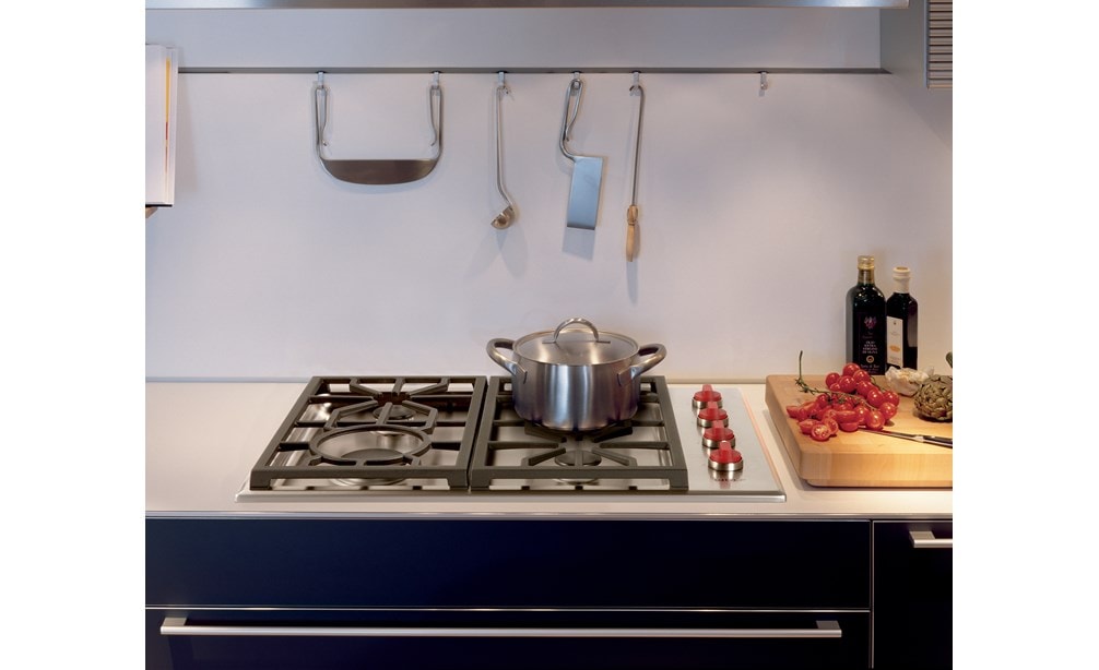 The Wolf 30" Professional Gas Cooktop 4 Burner (CG304P/S) featuring signature red knobs set with stainless steel utensil holder