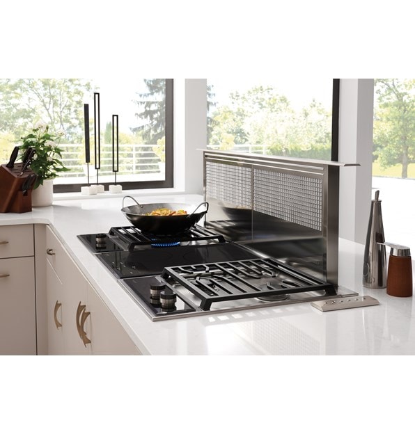 The Wolf 15" Transitional Induction Cooktop (CI152TF/S) shown set flush in artistic black and white speckled granite countertop