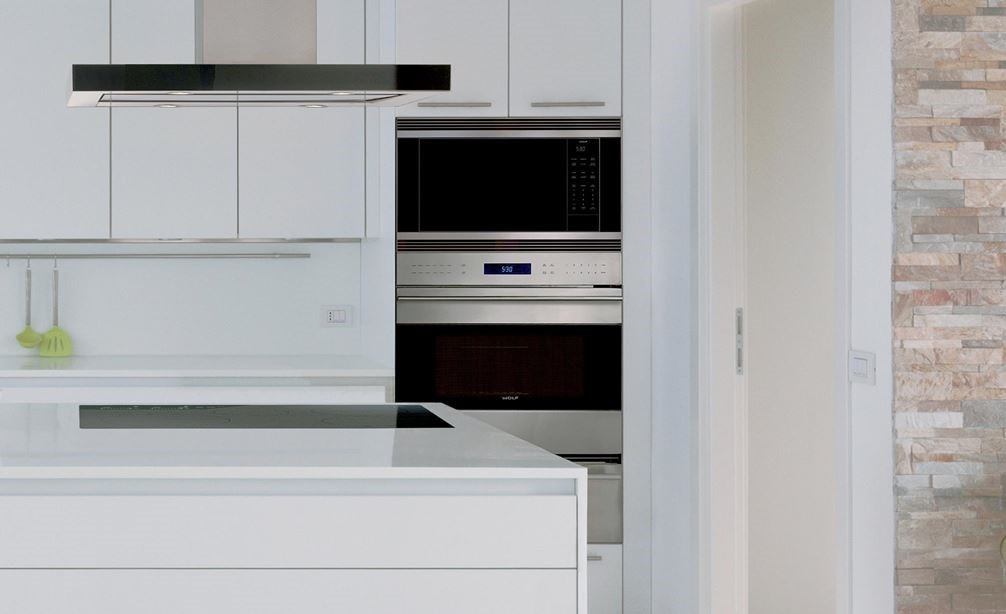 The Wolf 30" E Series Transitional Classic Single Oven (SO30TE/S/TH) shown with 42" Cooktop Island Hood (VI42B) set in sleek cabintery.