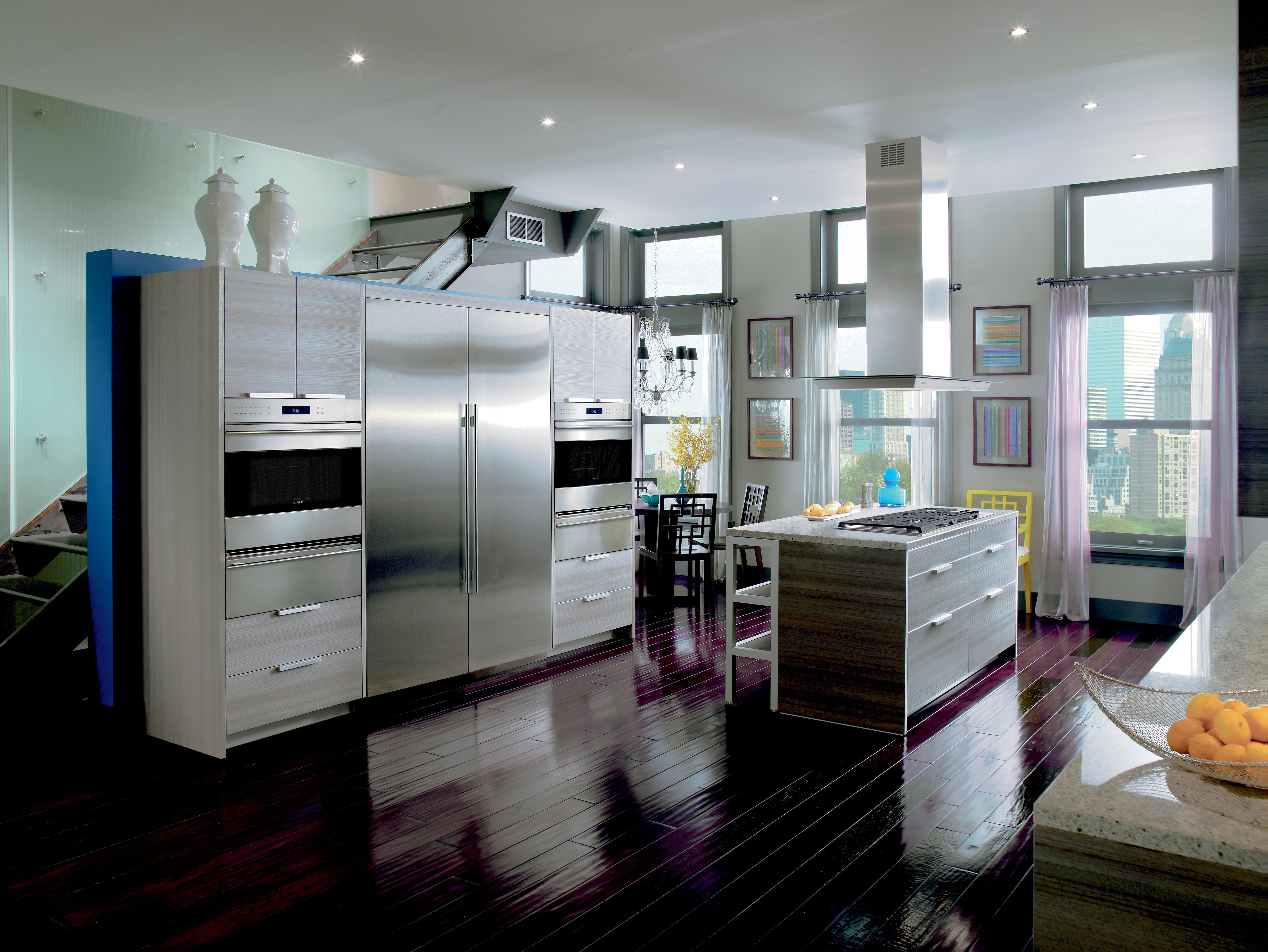 The Wolf 45" Cooktop Island Hood (VI45G) displayed in a large open modern kitchen featuring glossy wood flooring
