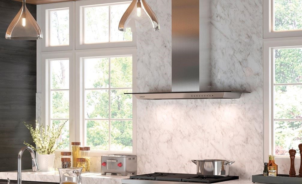 The Wolf 36&quot; Cooktop Wall Hood - Glass (VW36G) shown centered on large textured backsplash between large windows in open kitchen design